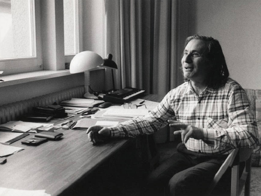 An image of composer alfred schnittke, laughing at his desk